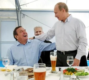 Володимир Путін обіймає Герхарда Шредера за столом з пивом