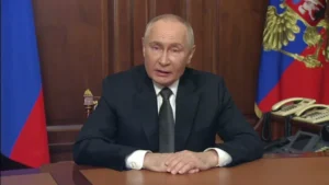 Володимир Путін за столом у кабінеті з прапорами Росії