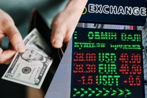 Курси долара та євро на табло обмінника з купюрою в руках