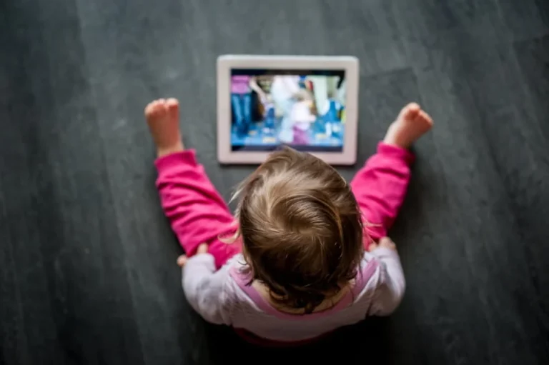 Трёхлетний ребёнок лежит на полу с планшетом