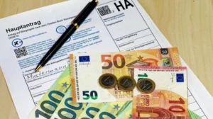Заявление на Bürgergeld с банкнотами евро и ручкой для заполнения