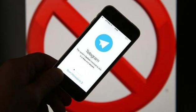 Смартфон с Telegram на фоне знака запрета из-за санкций США