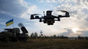 Український дрон у польоті над технікою з прапором України