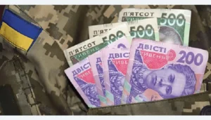 Банкноти гривень у кишені військової форми з прапором України