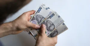 Руки тримають пачки банкнот по 500 гривень на витрати родини в Києві