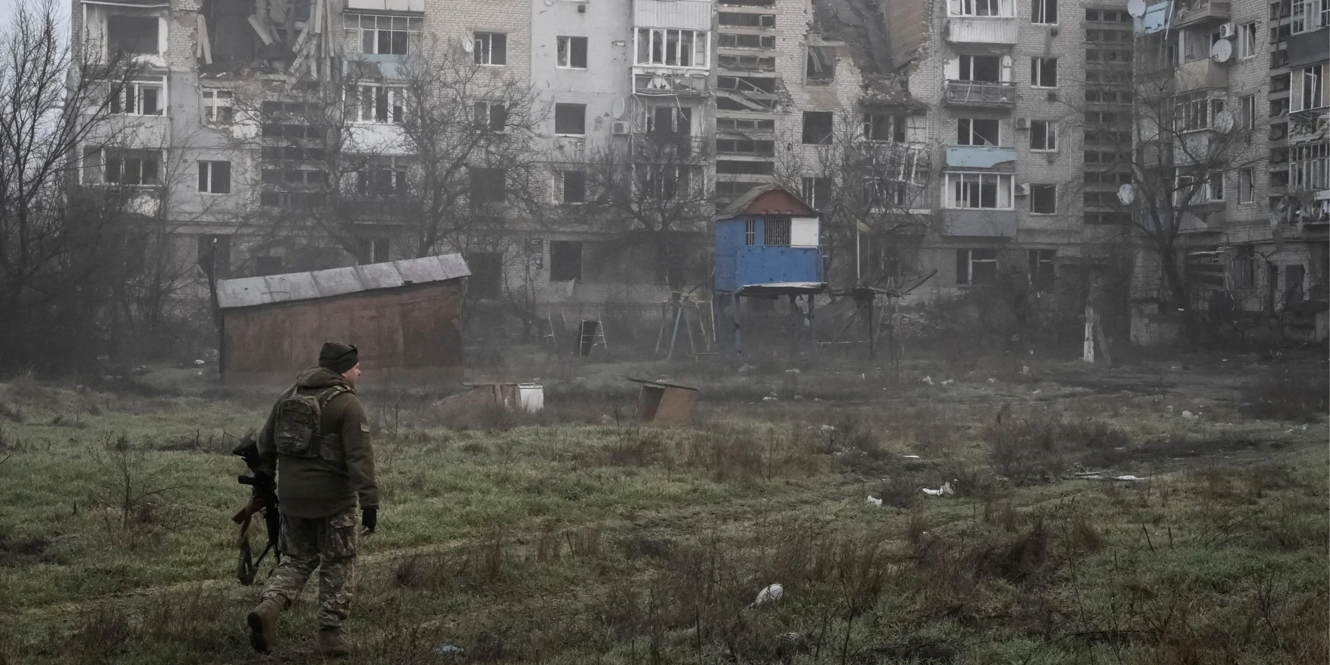 Військовий на тлі зруйнованих будинків на Оріхівському напрямку в негоду