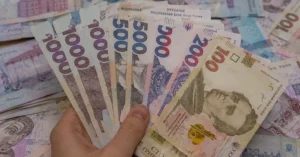 Рука держит банкноты украинской гривны номиналом 100–1000