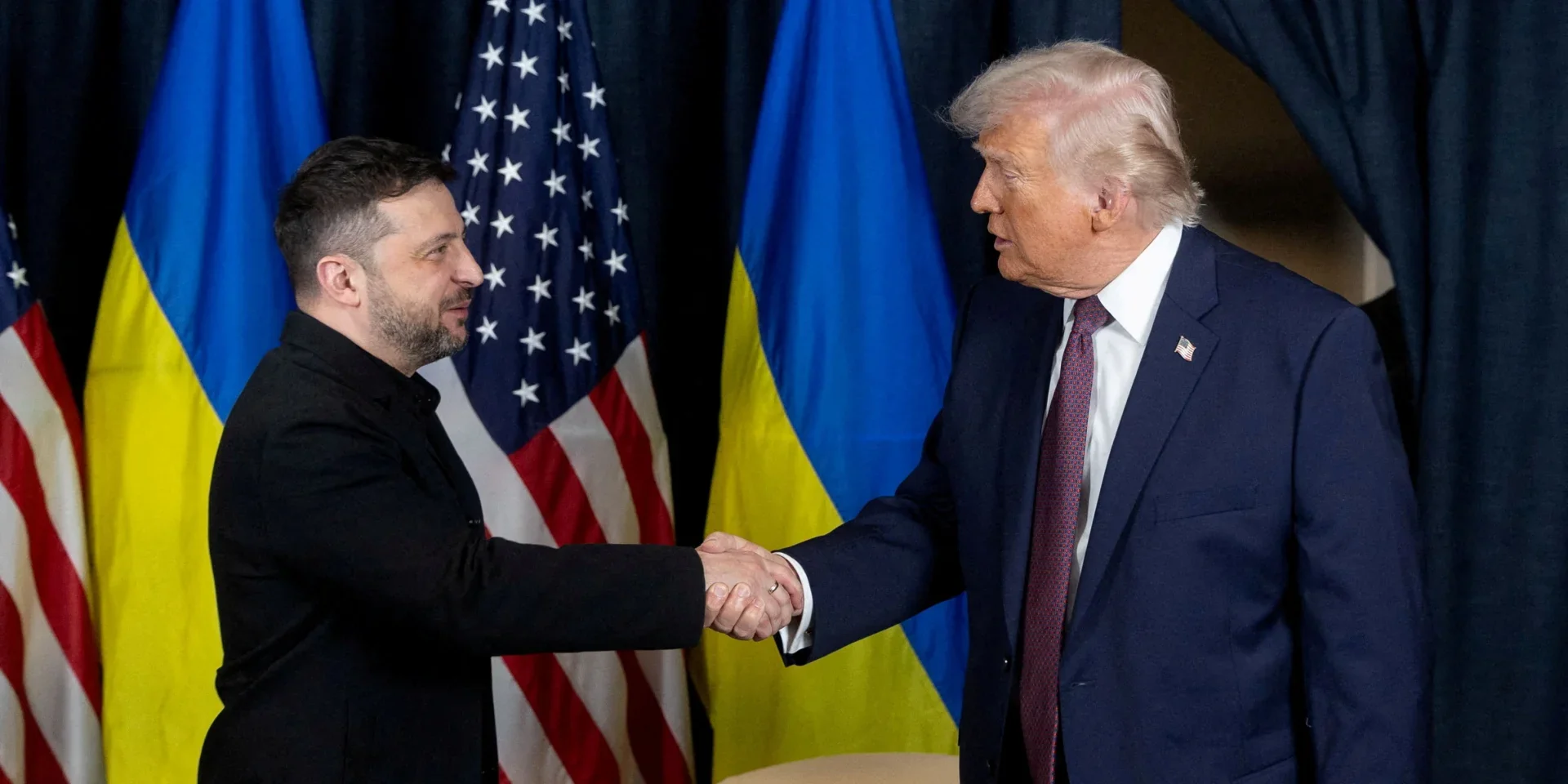 Зеленский и Трамп пожимают руки на фоне флагов Украины и США