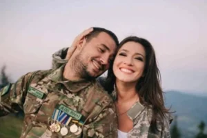 Усміхнене подружжя в камуфляжі обіймається на тлі гір