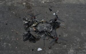 Обгорілі уламки FPV-дрона з пропелерами лежать на мокрій брудній поверхні