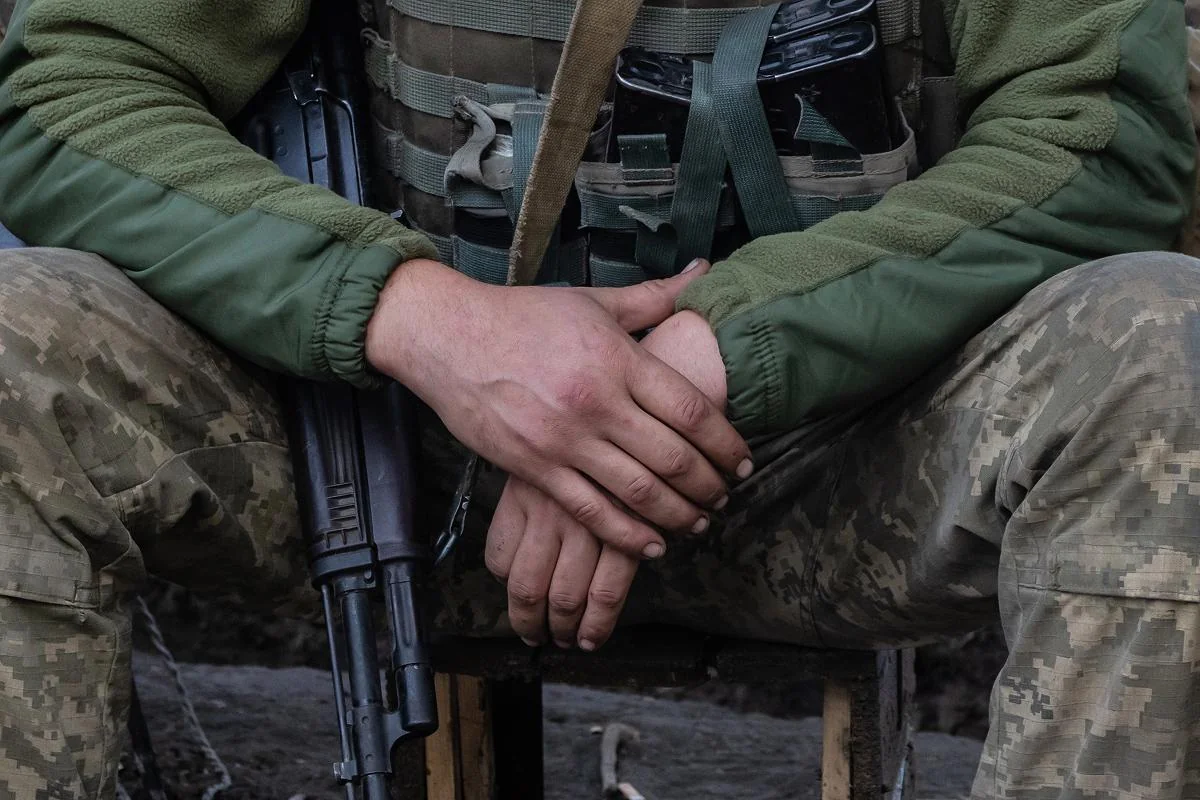 Двоє військовослужбовців у камуфляжній формі зі зброєю покладають руки одна на одну